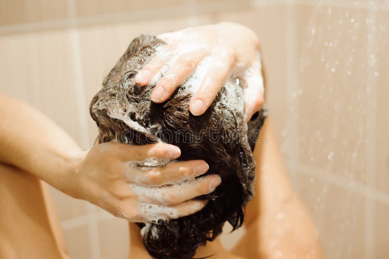 Beautiful woman taking a shower. Washing hair with Shampoo