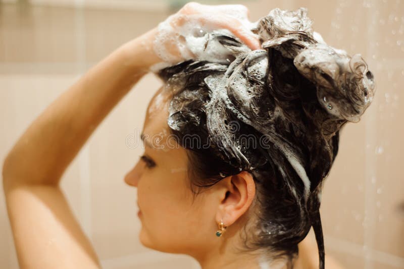 Beautiful woman taking a shower. Washing hair with Shampoo