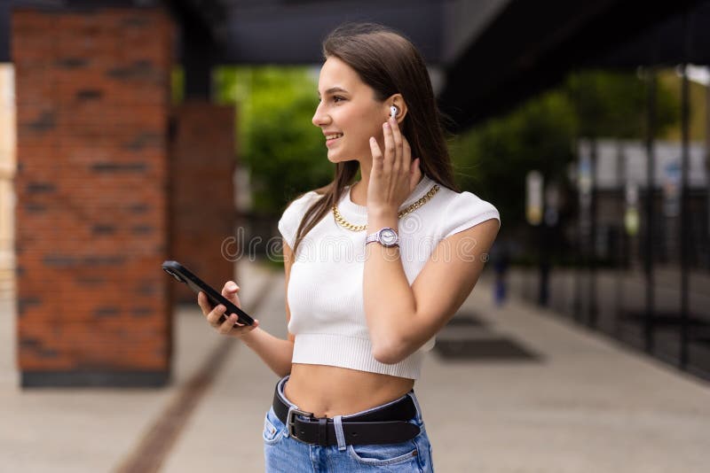 Beautiful woman talking phone on air pods on the street