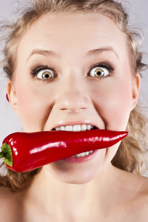 Beautiful woman teeth eating red hot chili pepper