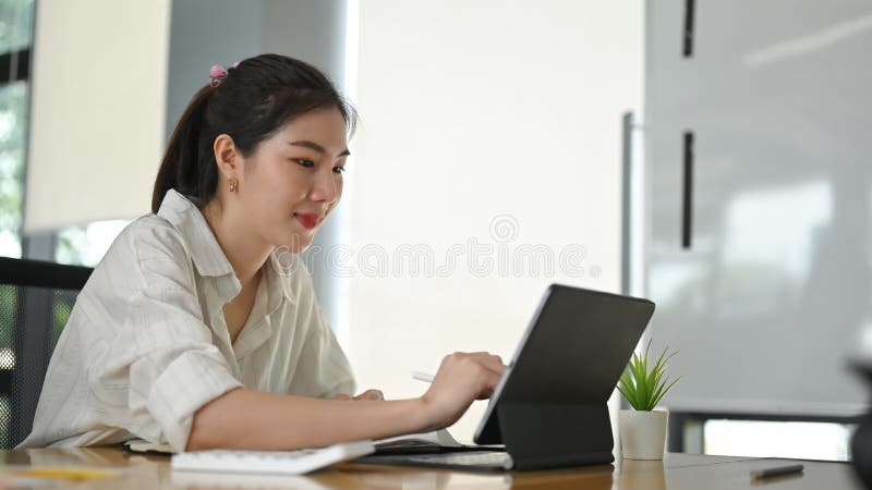 A beautiful woman is using a computer tablet with a keyboard case. royalty free stock photography