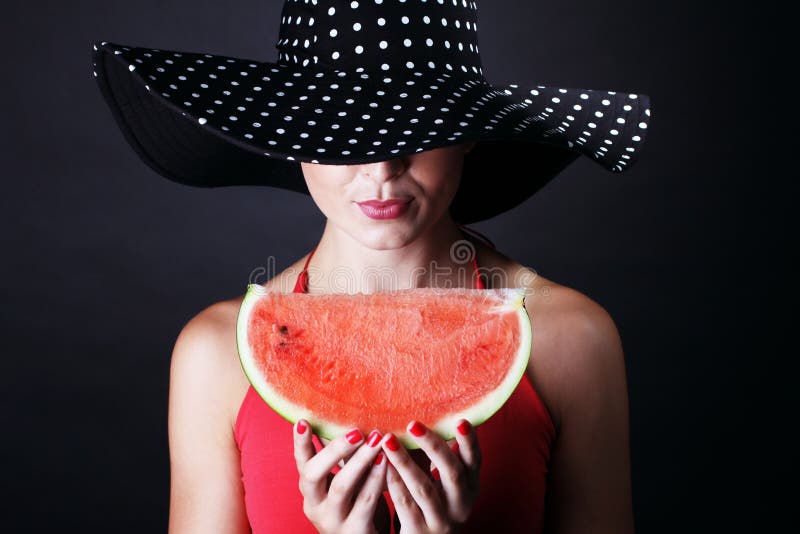 Beautiful woman with watermelon and hat on black background