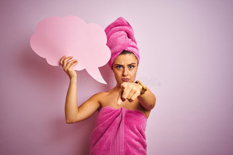 Beautiful woman wearing towel holding cloud speech bubble over isolated pink background pointing with finger to the camera and to