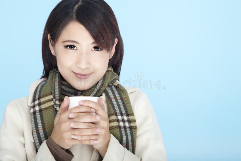 Krásna žena nosiť zimné oblečenie a drží šálku kávy.