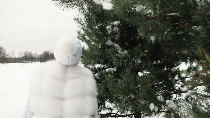 Beautiful woman in white dress runs and rejoices in the winter.