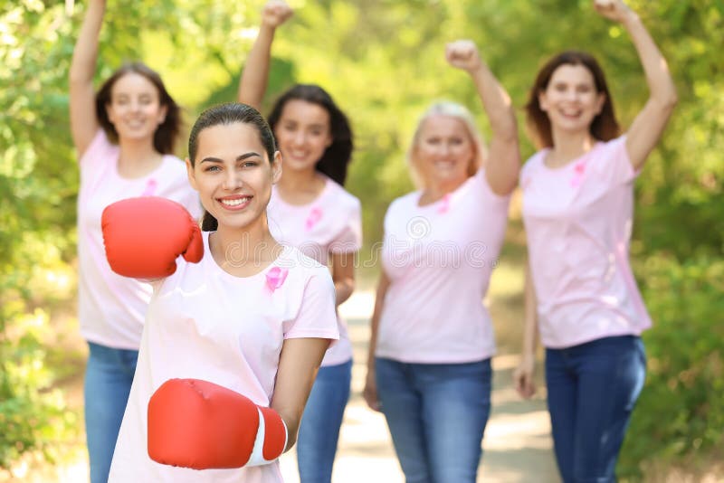 Beautiful woman with pink ribbon and boxing gloves outdoors. Breast cancer concept royalty free stock photography Beautiful woman with pink ribbon and boxing gloves outdoors. Breast cancer concept royalty free stock photography