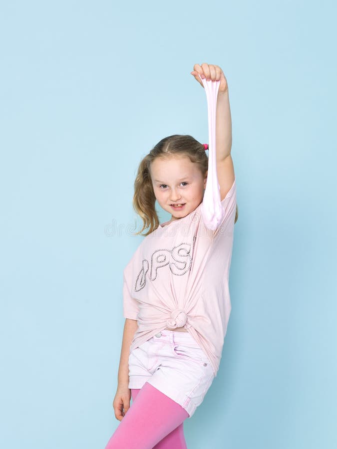 Beautiful 8 year old girl is playing with pink slime in front of blue background stock images Beautiful 8 year old girl is playing with pink slime in front of blue background stock images
