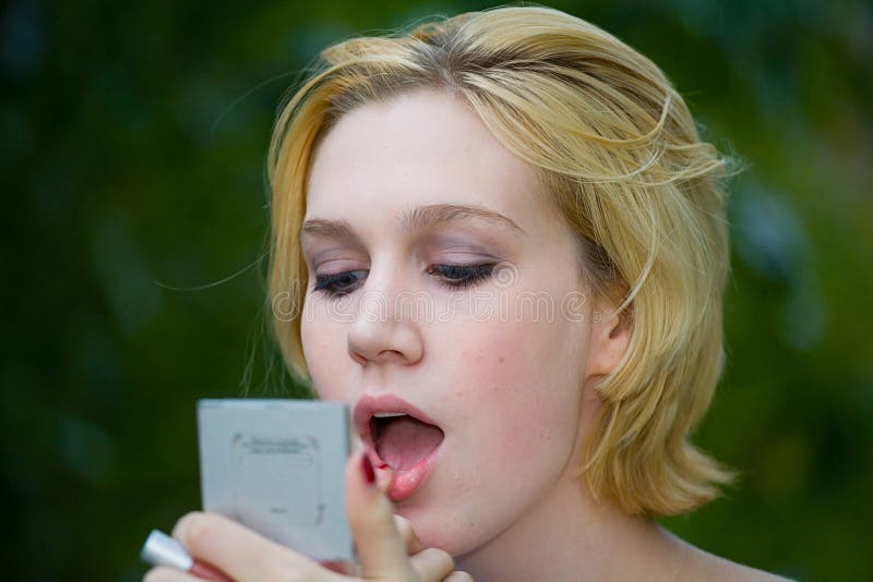 Beautiful Yong Blonde Girl with Blue Eyes Putting on Makeup