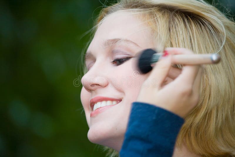 Beautiful Yong Blonde Girl with Blue Eyes Putting on Makeup