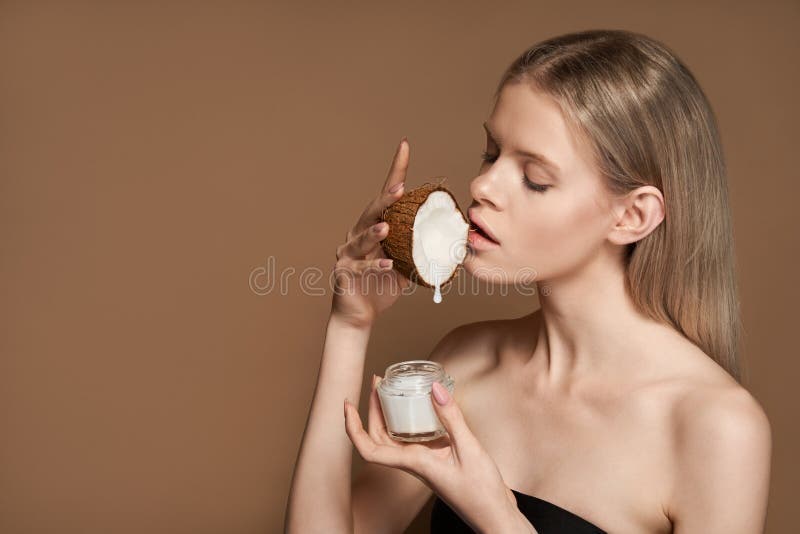 Beautiful woman hold coconut oil drop fall in cream jar isolated on background.