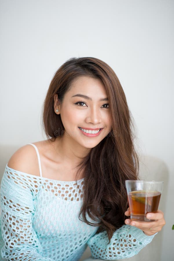 Beautiful young asian woman drinking her morning tea over a breakfast at home.