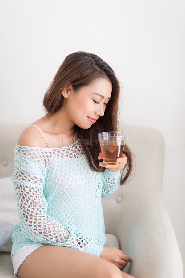 Beautiful young asian woman drinking her morning tea over a breakfast at home.