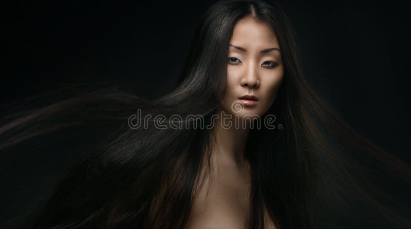 Beautiful young asian woman with long hair on dark background