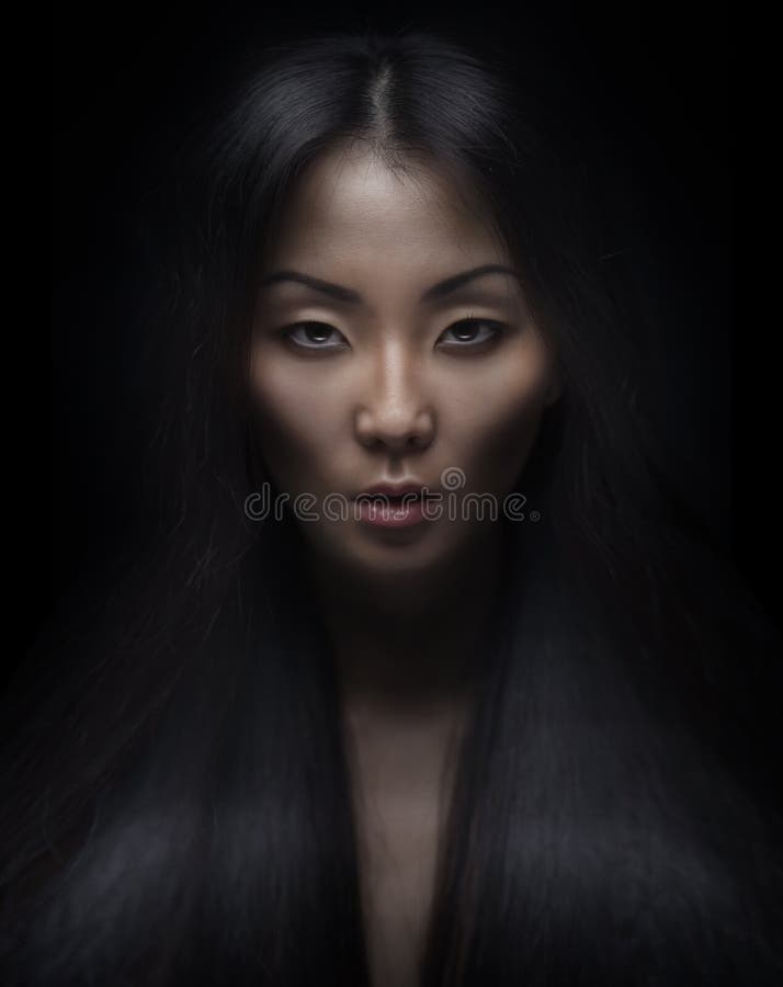 Beautiful young asian woman with long hair on dark background