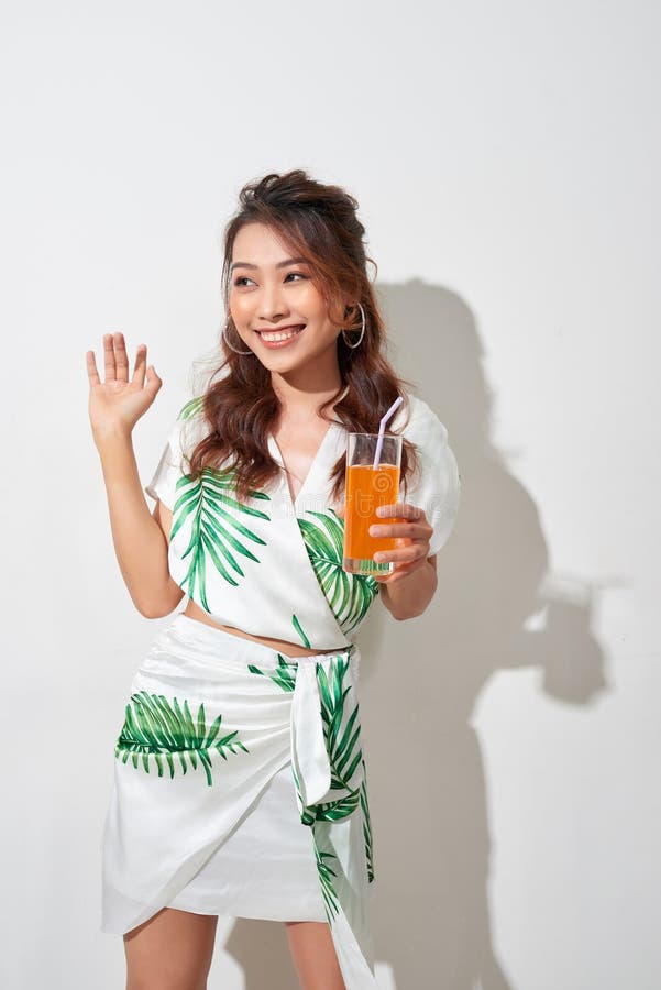 Beautiful young Asian woman with orange juice in tropical shirt on white background royalty free stock images Beautiful young Asian woman with orange juice in tropical shirt on white background royalty free stock images