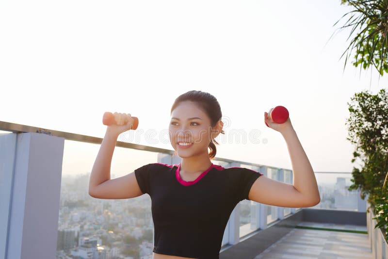 Beautiful young Asian woman practicing with dumbbells outdoor. Sporty girl royalty free stock photos Beautiful young Asian woman practicing with dumbbells outdoor. Sporty girl royalty free stock photos