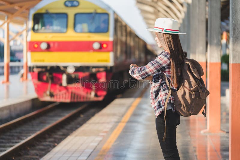 Beautiful young asian woman traveler looking clock with brown bag ,Waiting for train at train station, Chinese tourists, Travel and vacation concept