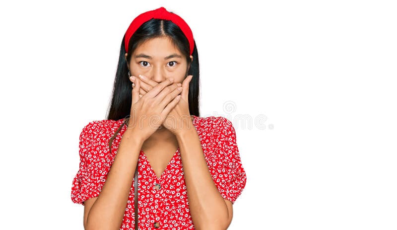 Beautiful young asian woman wearing dress and vintage camera shocked covering mouth with hands for mistake stock photo
