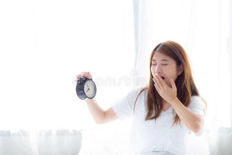 Beautiful young asian woman yawn wake up in morning annoyed alarm clock holding hand royalty free stock photography Beautiful young asian woman yawn wake up in morning annoyed alarm clock holding hand royalty free stock photography