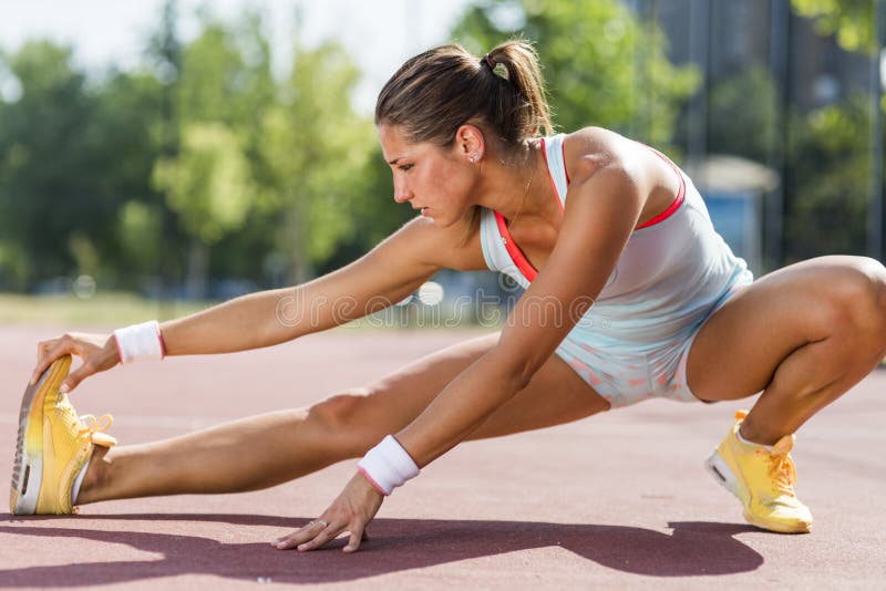 Beautiful young athletic woman stretching in summer stock image