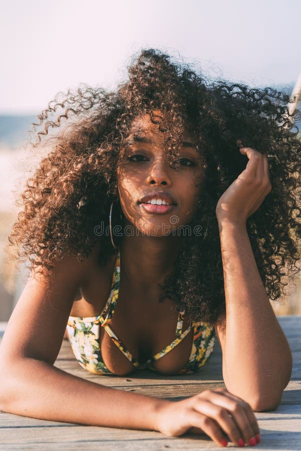 Beautiful young black woman lying down in a wooden foot bridge