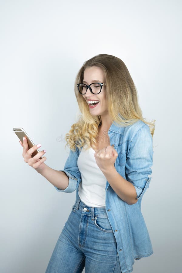 Beautiful young blond woman holding smartphone looks happy close up white background stock image Beautiful young blond woman holding smartphone looks happy close up white background stock image