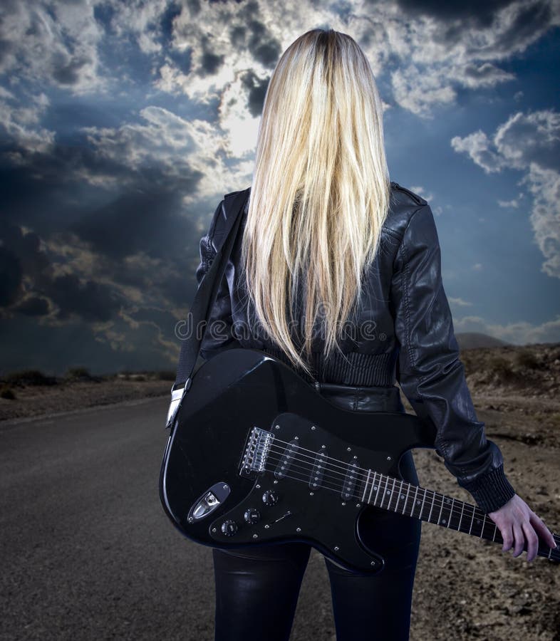 Beautiful young blonde dressed in black leather with electric gu