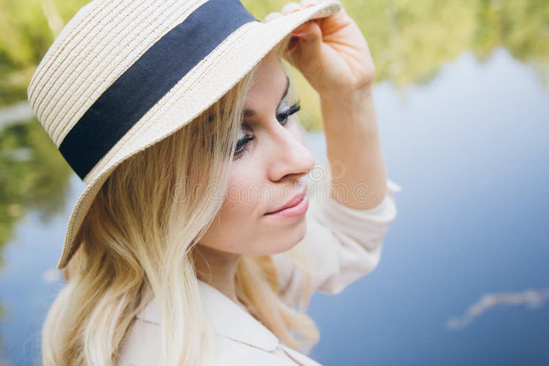 Girl in a hat resting on the autumn lake on the bridge