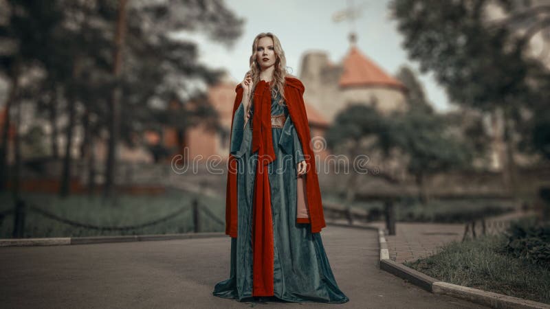 Charming young blonde princess in the medieval green dress with a red cape