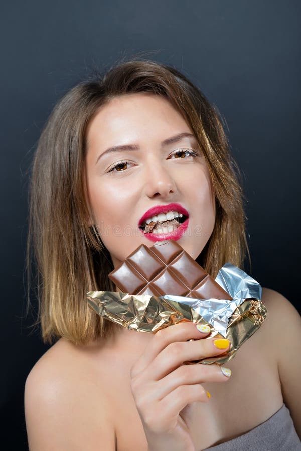 Beautiful young blonde woman eating chocolate bar. stock photos Beautiful young blonde woman eating chocolate bar. stock photos