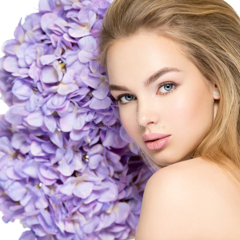 Beautiful young blonde woman with flowers near face