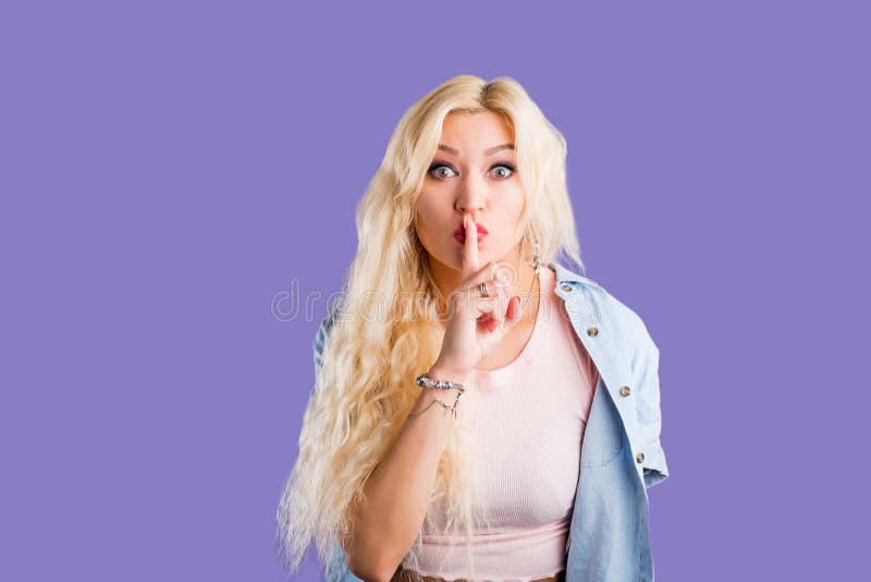 A beautiful young woman with her finger to her lips saying shh stock photos A beautiful young woman with her finger to her lips saying shh stock photos