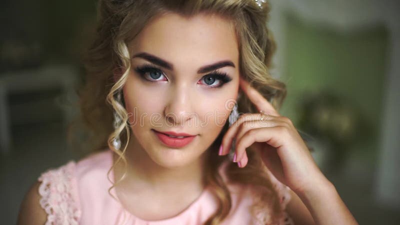 Beautiful Young Bride. Stylish Woman Fiancee with Bridal Hairstyle, Event Makeup and Jewelry. He looks up at the camera.