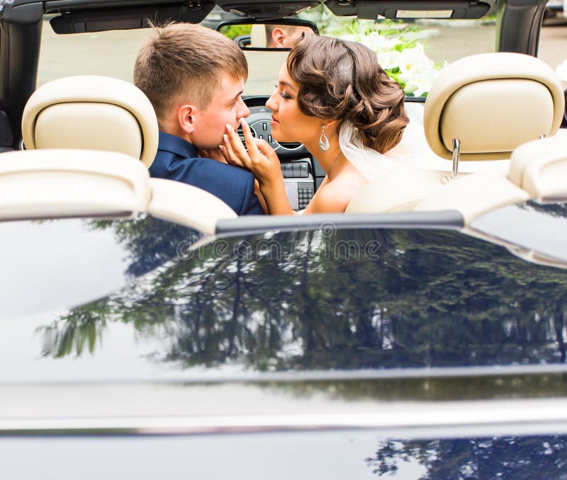 Beautiful young couple bride and groom posing in cabriolet royalty free stock photos