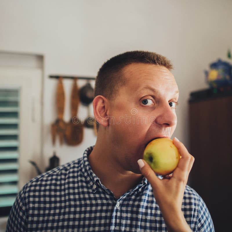 Beautiful young couple eating apple together in the kitchen stock image Beautiful young couple eating apple together in the kitchen stock image