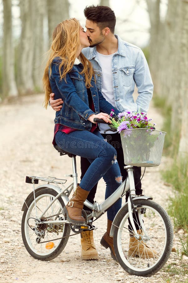 Beautiful young couple in love on bike in the park.