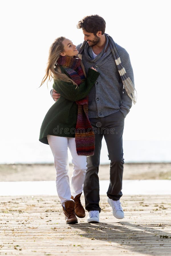 Beautiful young couple in love walking in a cold winter on the b