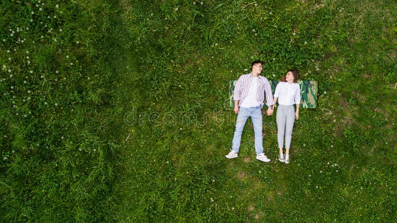 Beautiful in love young couple lying on the grass, view from above