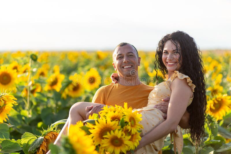 A beautiful young couple a man and a woman, embrace in a field of sunflowers at sunset