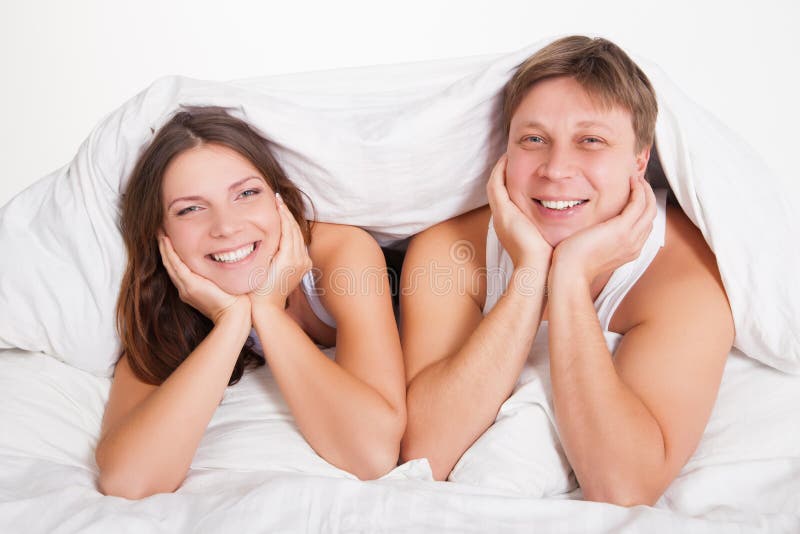 Beautiful young couple relaxing in bed at home stock images