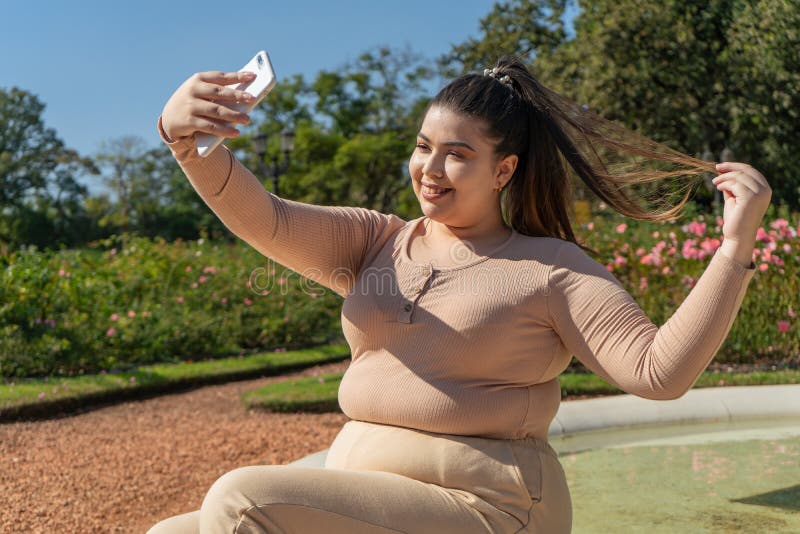 Beautiful Young Curvy Girl Taking a Selfie while Smiling Happily