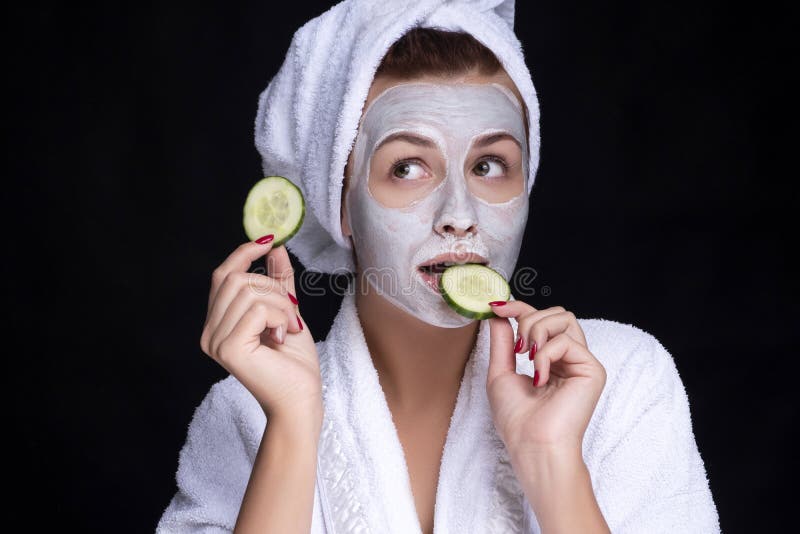 Beautiful young european woman apply clay mask on her face with towel on her head and cucumbers on her eyes. beauty spa concept royalty free stock photo Beautiful young european woman apply clay mask on her face with towel on her head and cucumbers on her eyes. beauty spa concept royalty free stock photo