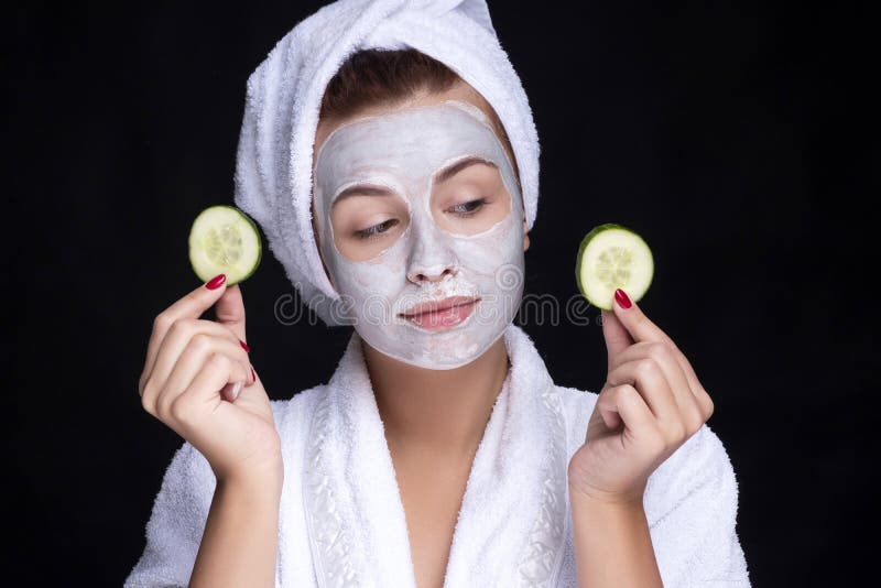 Beautiful young european woman apply clay mask on her face with towel on her head and cucumbers on her eyes. beauty spa concept royalty free stock image Beautiful young european woman apply clay mask on her face with towel on her head and cucumbers on her eyes. beauty spa concept royalty free stock image