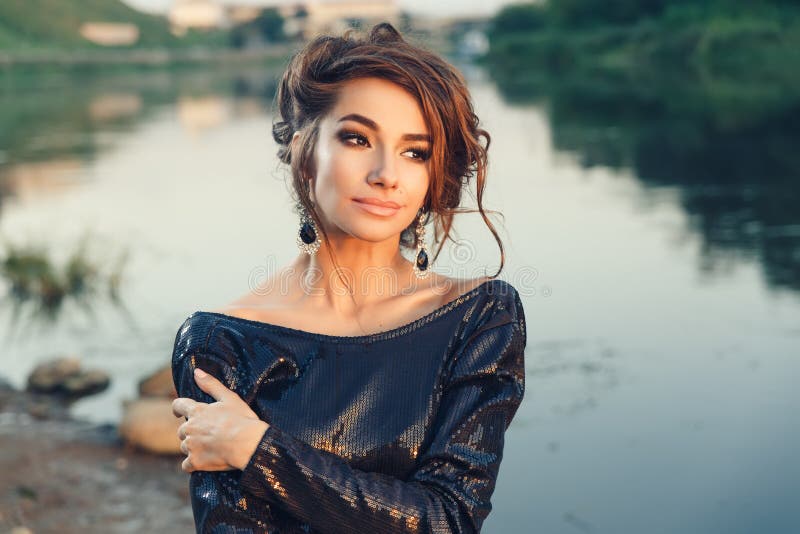 Beautiful young fashionable woman posing in dress at the river coast