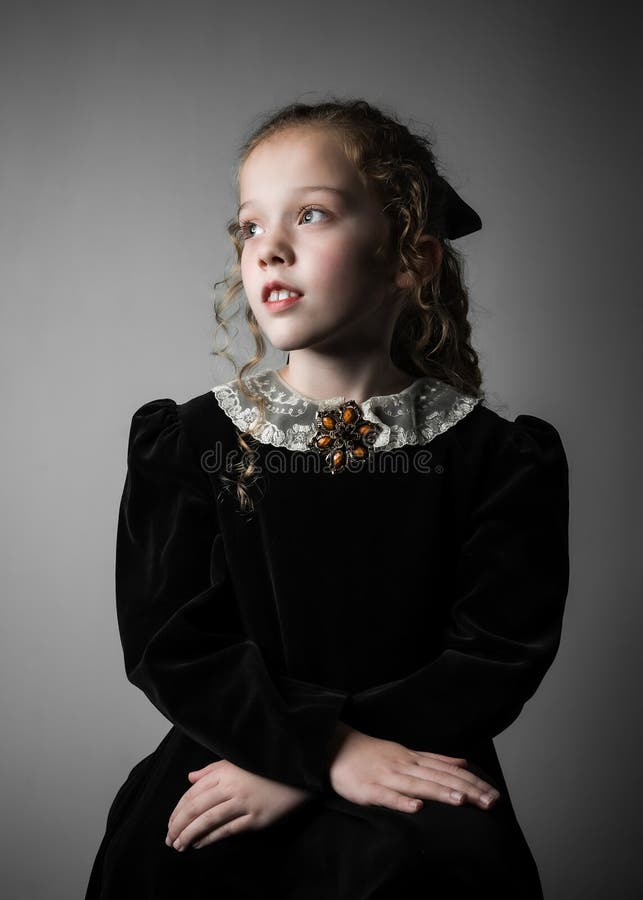 Beautiful young girl in black 1890s English Victorian 18th century child period dress elegant white lace collar antique broach