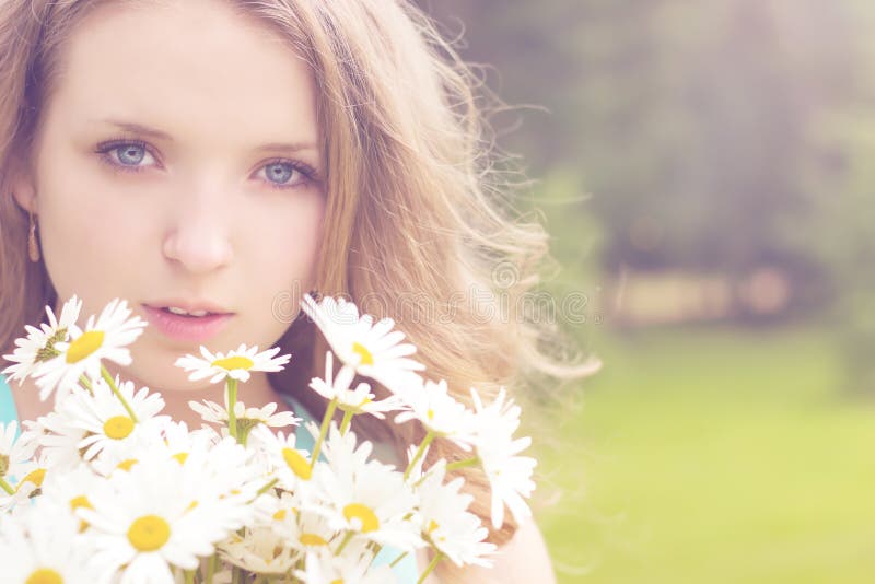 Beautiful young girl with a bouquet of daisies with white hair stands in a Park on a Sunny summer day