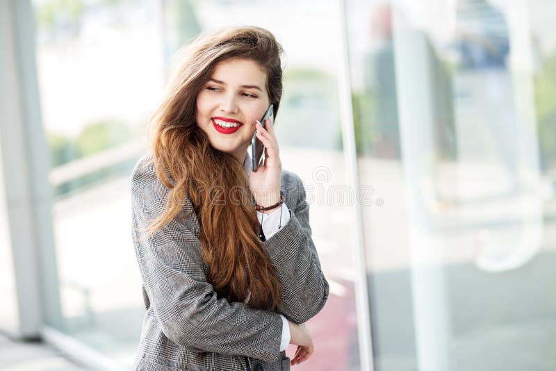 Beautiful young girl communicates on the smartphone. Red lipstick. The concept of fashion, business, communication and lifestyle royalty free stock photos Beautiful young girl communicates on the smartphone. Red lipstick. The concept of fashion, business, communication and lifestyle royalty free stock photos