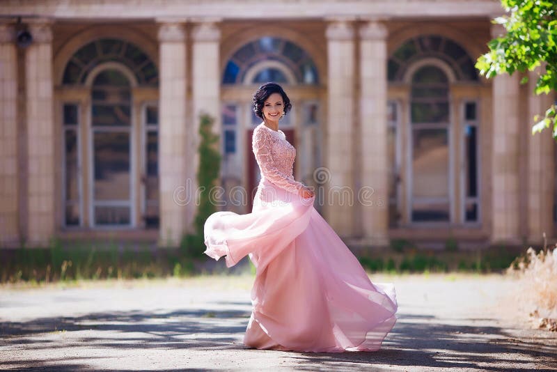 Beautiful young girl with elegant dress and nice smile walking in the street. Lifestyle concept. Youth and happiness.