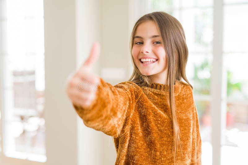 Beautiful young girl kid at home doing happy thumbs up gesture with hand