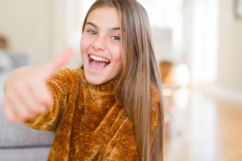 Beautiful young girl kid wearing casual sweater doing happy thumbs up gesture with hand